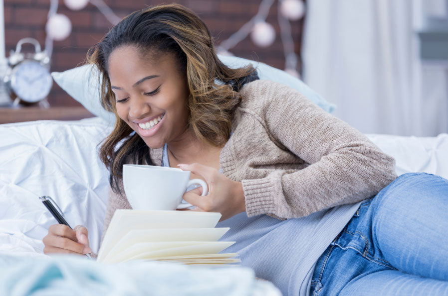 Young Black Woman writing in Journal