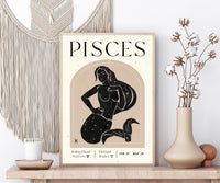 A framed Pisces zodiac art print displayed on a wooden shelf in a styled home decor setting, featuring a black line art illustration of a mermaid on a beige background with cream text.