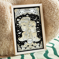 poster leaning on chair Gemini cosmic zodiac portrait featuring two feminine figures surrounded by stars, Gemini constellation, Mercury symbol, and Air element