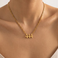 A close-up of a gold chain necklace worn on a model's neck, featuring a small pendant with the number 444.