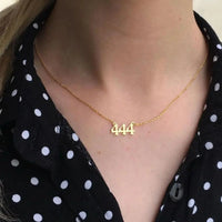 Gold 444 angel number necklace on woman's neck, spiritual jewelry, black polka dot shirt