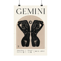 A vertical Gemini zodiac poster with black text and black illustrated female figures on a warm cream background, hanging against a white wall with two black clips.