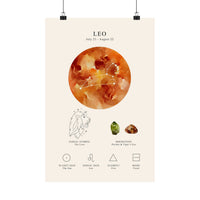 A vertical art print poster featuring the Leo zodiac sign, hanging from two black binder clips against a plain white background. The poster has a warm cream background with a large orange and brown watercolor sun graphic, a line drawing of a lion, crystals, and astrological icons with labels.