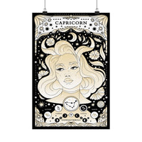 A vertical Capricorn zodiac poster with an ornate black, cream, and beige illustration of a woman's face surrounded by stars, crescent moons, flowers, and astrological symbols. The word 'CAPRICORN' appears at the top, and the poster is shown hanging against a white background with two black clips at the top.
