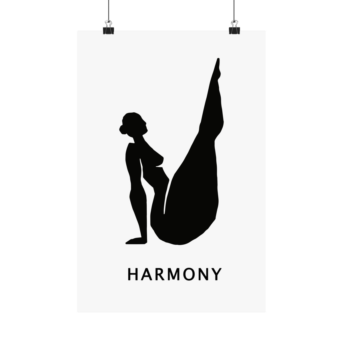 A minimalist black and white art print featuring a silhouette of a woman in a yoga pose with the word 'HARMONY' underneath, shown hanging from two black clips against a white background.