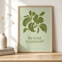 Minimalist botanical art print with olive-green leaves and the words “Be kind to yourself” on a pale green background, displayed in a natural wood frame.