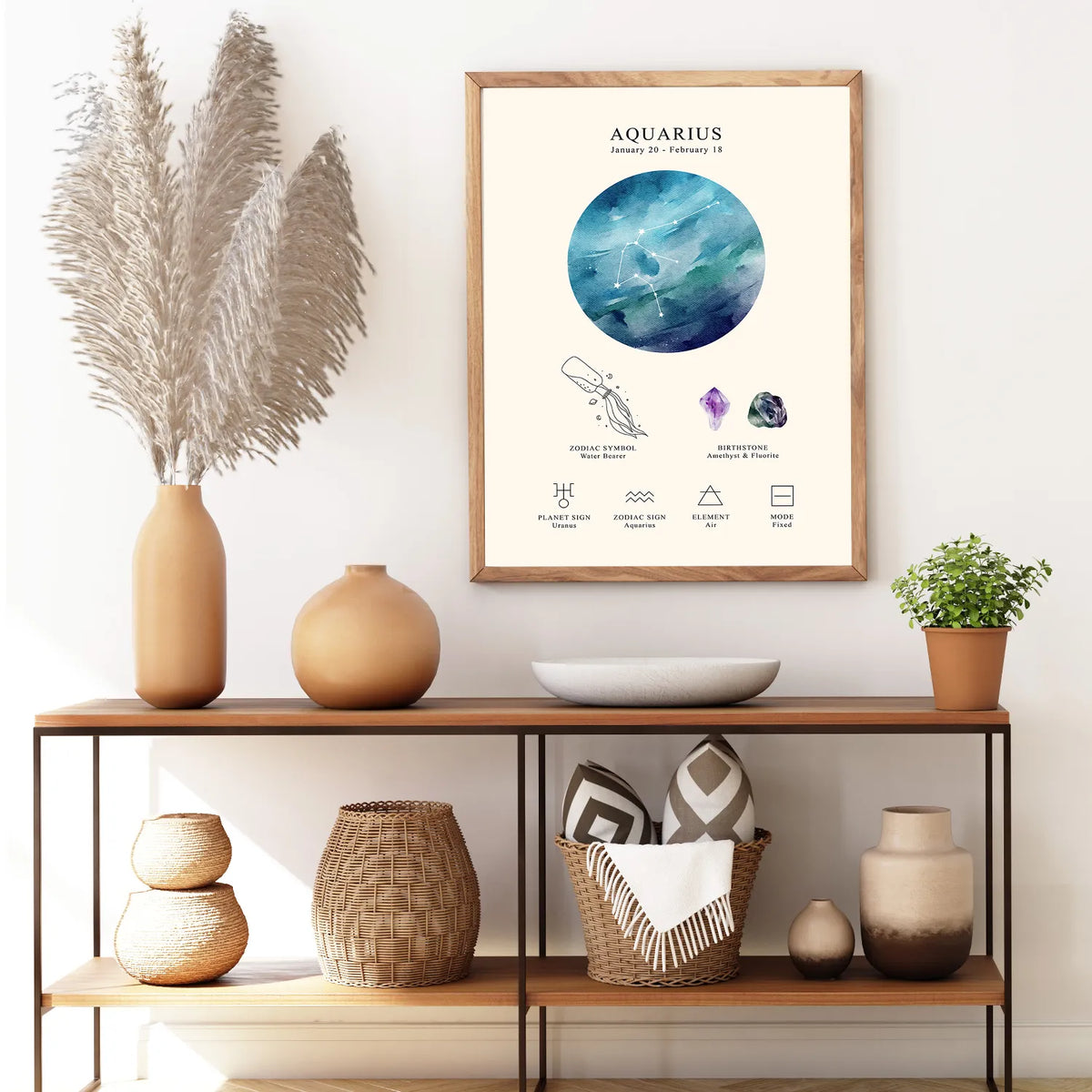 A framed art print featuring an Aquarius zodiac poster hangs on a white wall above a wooden console table styled with vases, a plant, and woven baskets.