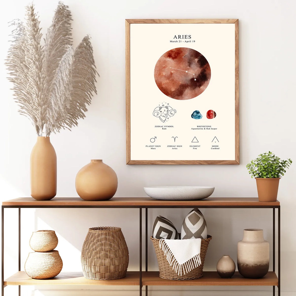 A framed Aries astrology poster hangs on a white wall above a wooden console table styled with ceramic vases, woven baskets, a bowl, and a small potted plant.