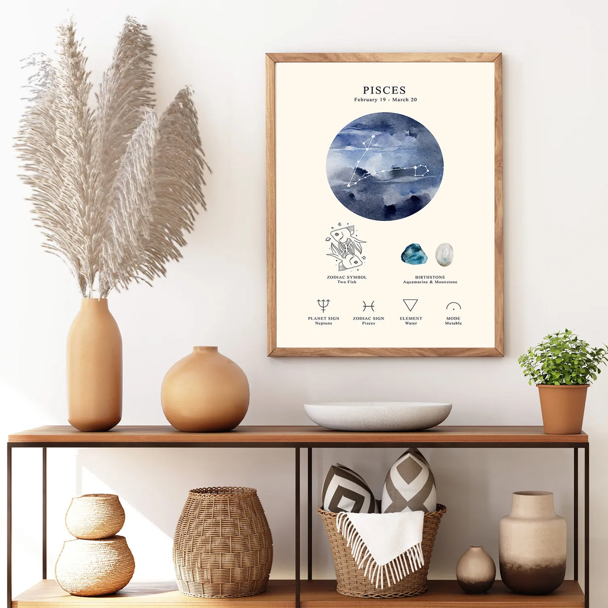 A framed Pisces zodiac art print hangs on a white wall above a wooden console table styled with vases, dried grass, a bowl, and a small plant.
