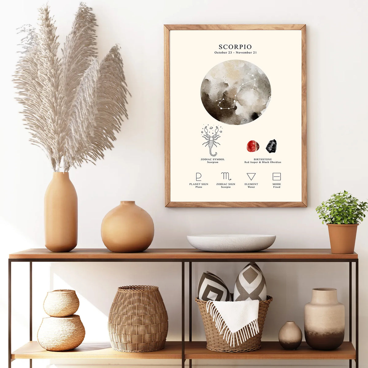 A framed astrology art print featuring the Scorpio zodiac sign with a watercolor moon illustration and astrological symbols, displayed on a wall above a wooden console shelf with decorative vases and a plant.