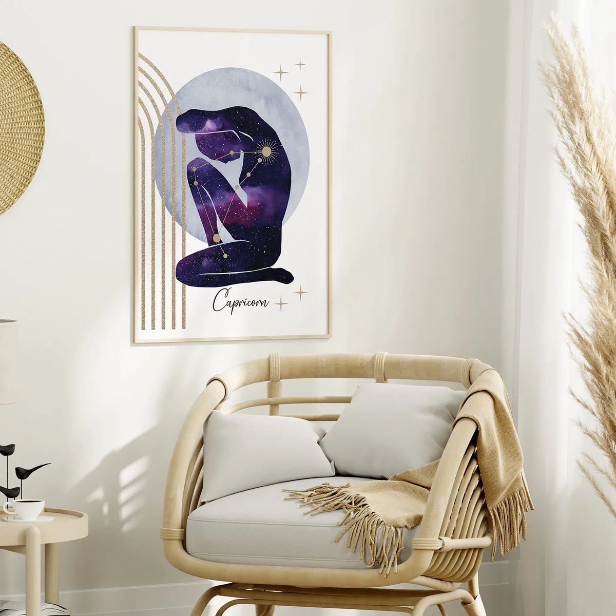 A framed wall art print featuring a seated Capricorn figure in a purple galaxy pattern against a pale blue moon, displayed above a rattan armchair in a styled room.