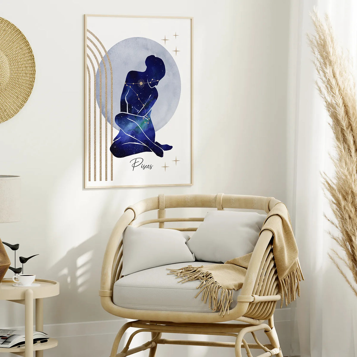 A framed art print featuring a Pisces zodiac sign illustration in deep blue and gold tones, styled on a white wall above a rattan armchair in a bright, modern room.