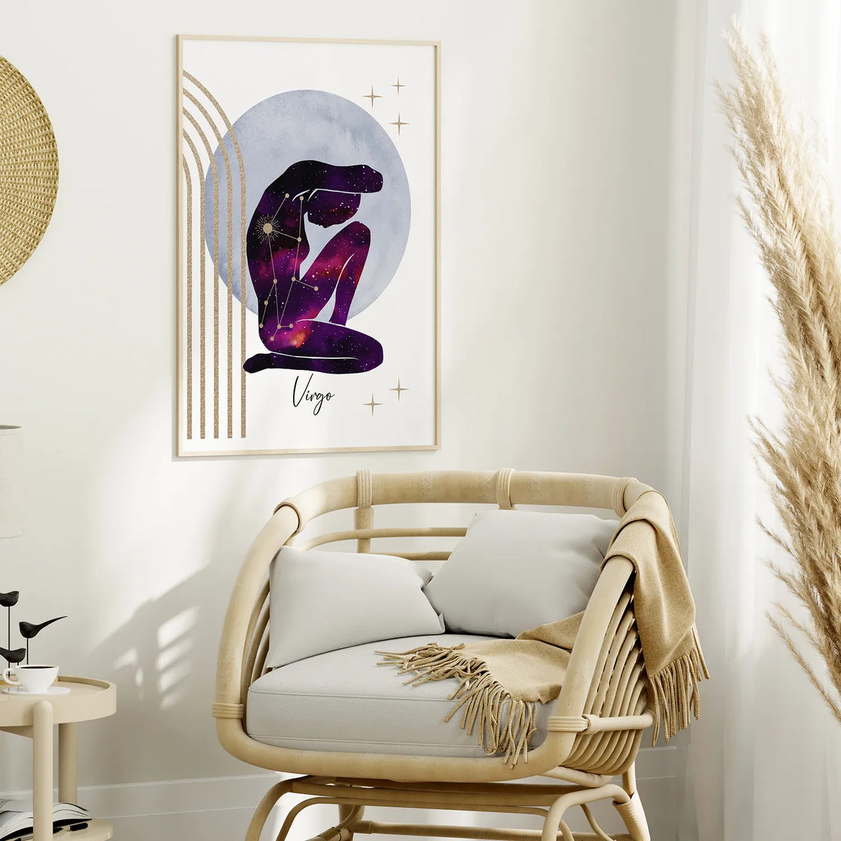 A framed wall art print featuring a stylized seated figure in a purple galaxy pattern against a pale blue circle, hung above a woven rattan armchair in a bright, neutral-toned room.
