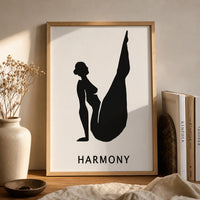 A minimalist black and white art print featuring a silhouette of a woman in a yoga pose with the word 'HARMONY' brown frame