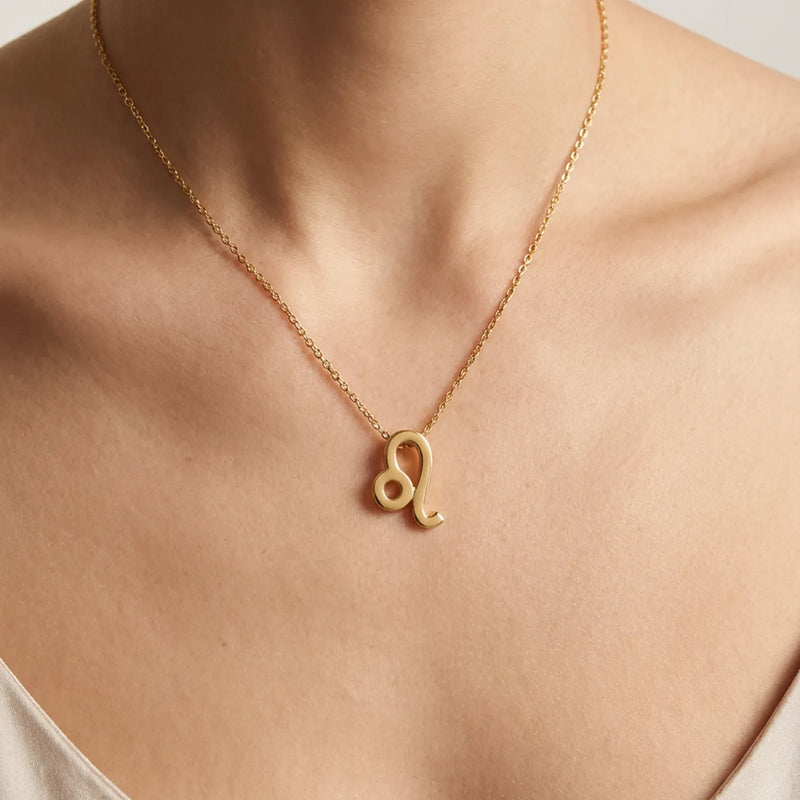 A gold chain necklace with a small leo zodiac sign pendant, worn on a model's neck.