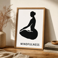 A minimalist black graphic print featuring a silhouette of a person in a seated meditation pose on a white background, with the word 'MINDFULNESS' in brown frame