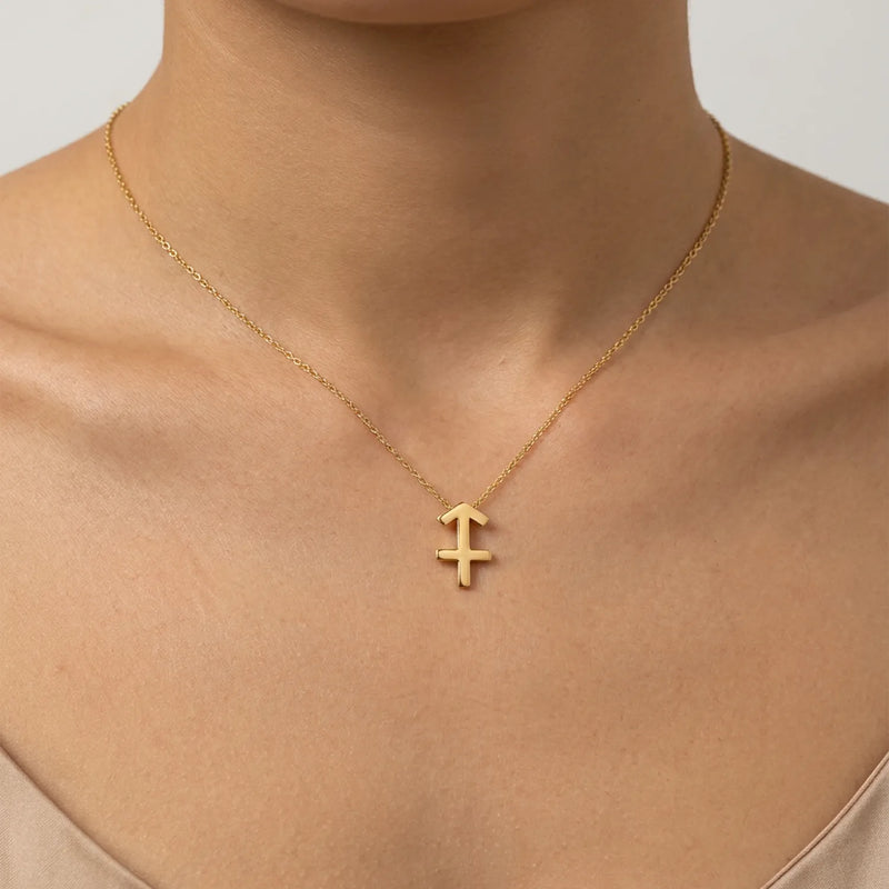 A delicate gold chain necklace with a sagittarius zodiac sign pendant, shown worn on a model's neck against a soft light gray background.