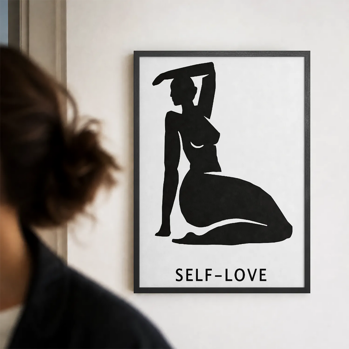 A minimalist black graphic print featuring a silhouette of a kneeling woman with one arm raised, above the text 'SELF-LOVE'  with black frame