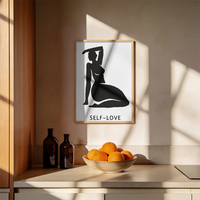 A minimalist black graphic print featuring a silhouette of a kneeling woman with one arm raised, above the text 'SELF-LOVE'  with brown frame