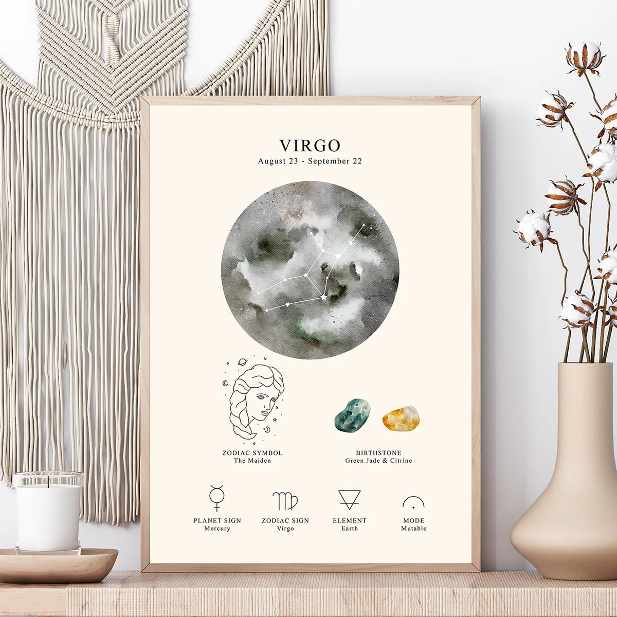 A framed astrology art print featuring a watercolor Virgo moon graphic and zodiac details, styled on a wooden surface with a macrame wall hanging, candle, and dried flowers in a vase.