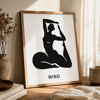 A minimalist art print featuring a black silhouette of a woman in a yoga pose on a white background, with the word 'MIND' kin brown frame