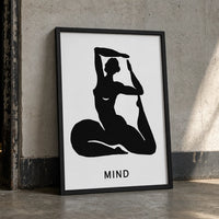 A minimalist art print featuring a black silhouette of a woman in a yoga pose on a white background, with the word 'MIND' in black frame